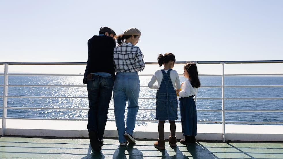 A family traveling on a ferry boat, looking out to sea